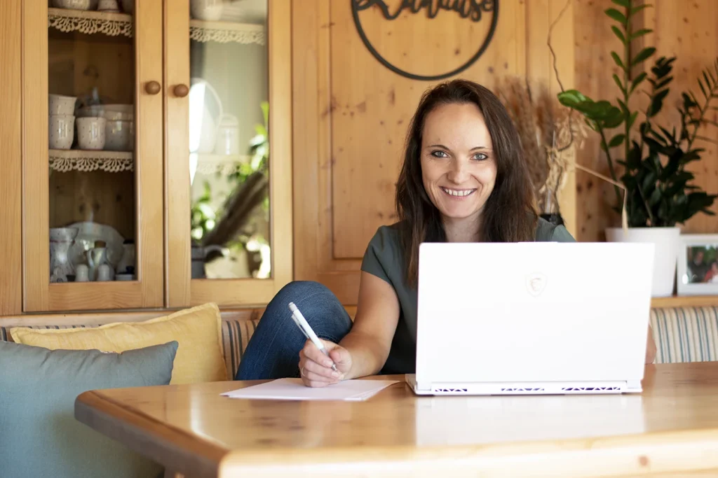 Portraitfoto Anja Moser sitzend am Tisch mit Laptop